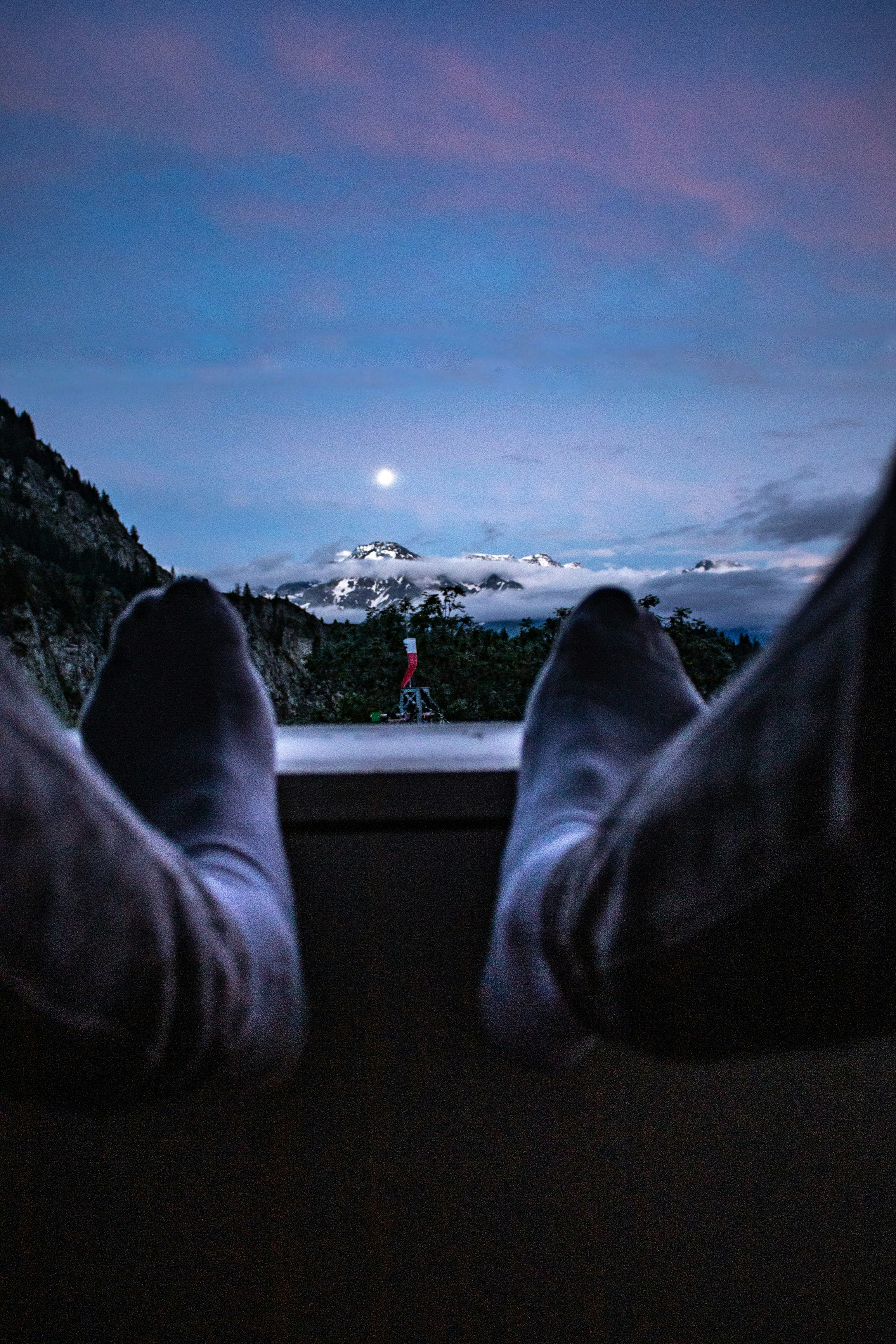 person in white pants and white sneakers sitting on the edge of a building